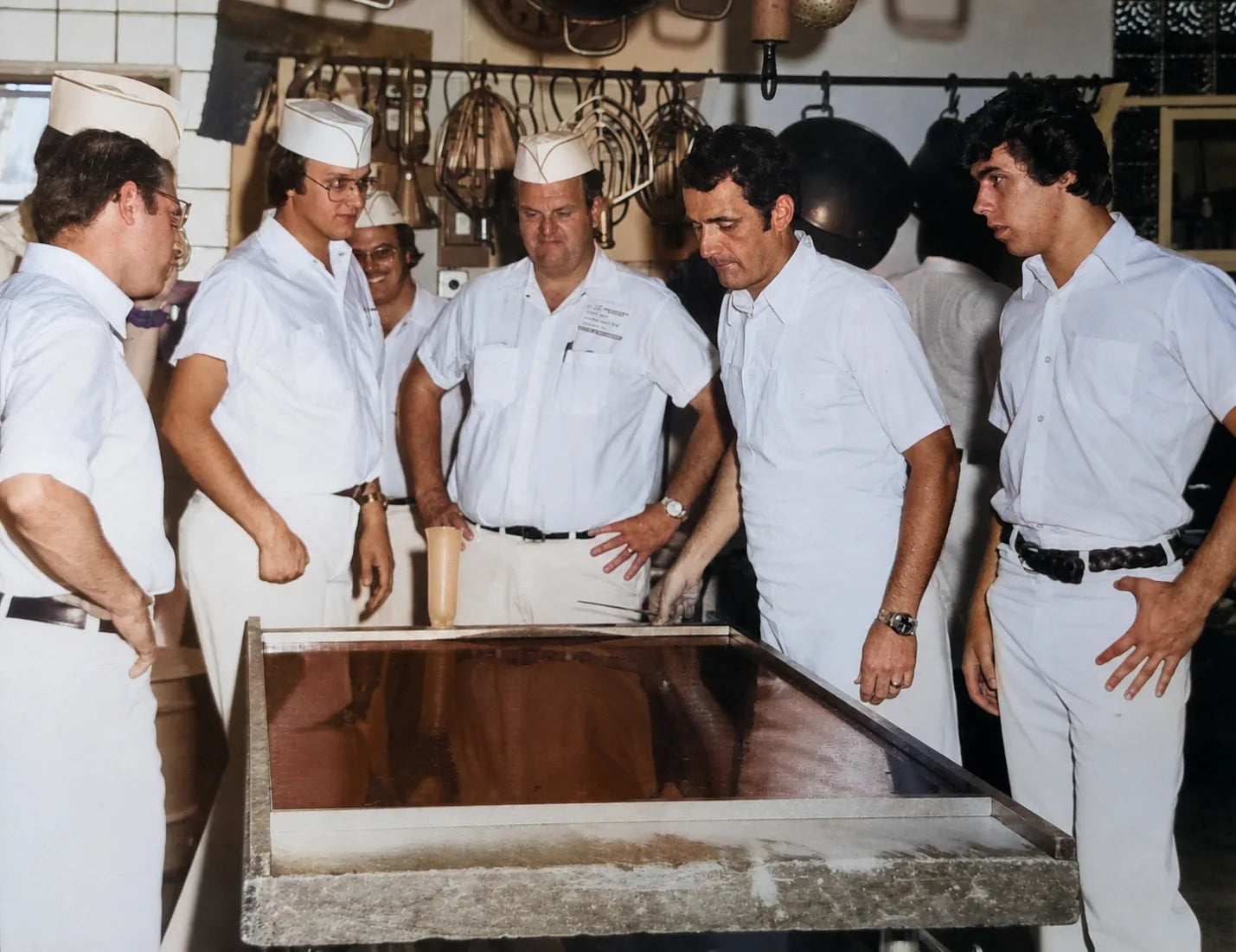 A group of fudge makers gathered around a fresh batch on a marble table